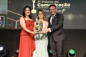 Clayton Conservani palestrando durante o lançamento do 4º Prêmio de Comunicação do Governo do Acre, com uma homenagem a Moisés Alencastro ao fundo.